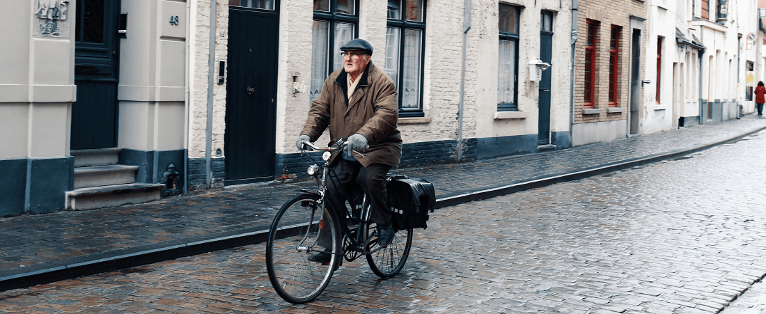 Man cycling on city road by May Lawrence