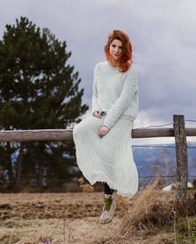 Mihaela, sitting on a fence in the countryside, with melancholic clouds overhead
