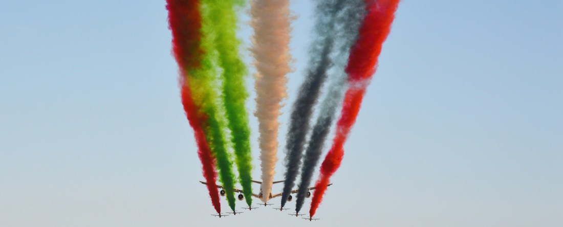 airplane releasing multi-coloured smoke in the shape of UAE flag