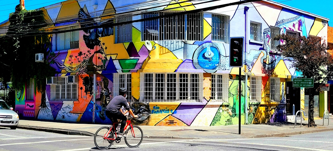 Cyclist crossing the street in front of colourful house in Chile