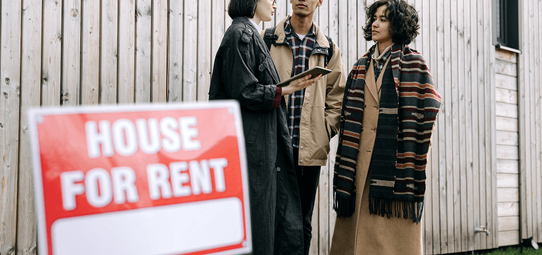 two prospective tenants meeting a realtor near a 'House for Rent' sign