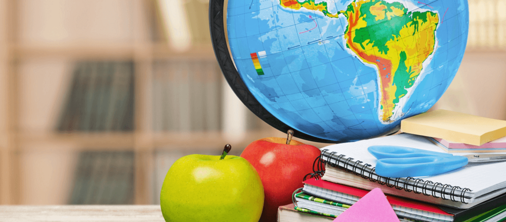 globe and apples next to educational supplies