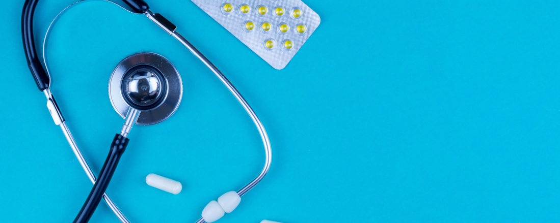 Stethoscope and medication on a cyan table