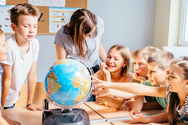 Children pointing at globe in the classroom