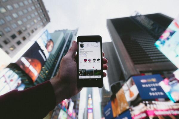 Using a phone with a high angle of a city centre in the background. Photo by Jakob Owens.